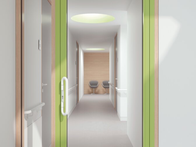 Verglaste Krankenhaustür mit grünem Rahmen ausgestattet mit einem Drückergriff in der Farbe Signalweiß aus Polyamid