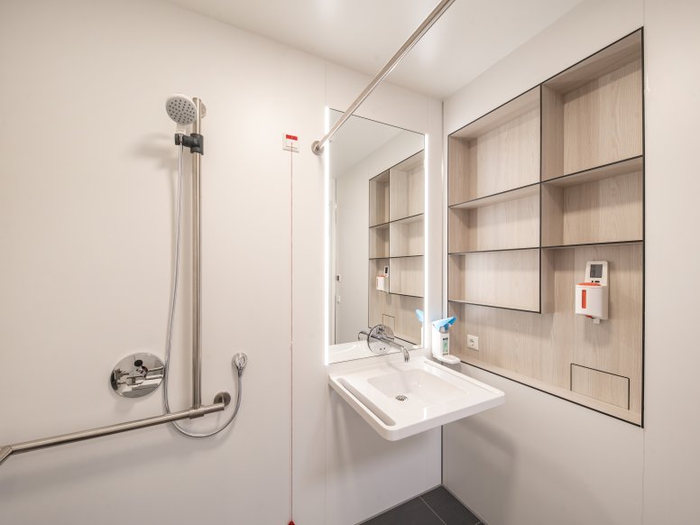 Patient bathroom with washbasin and shower area equipped with a washbasin and a shower holder in stainless steel
