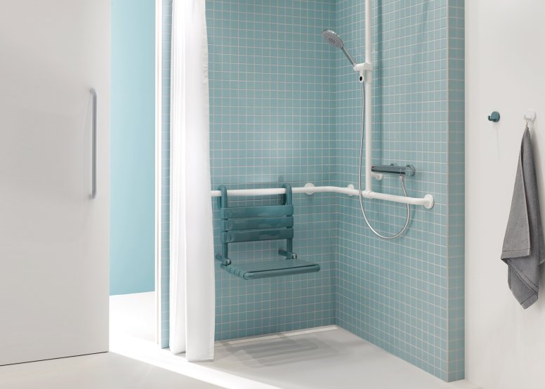Shower area of a patient bathroom in blue and white with a view through a sliding door